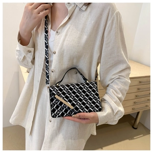 Detail of black and white checkered crossbody bag with gold metal trim and slim strap