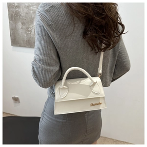 Detailed side view of a white leather crossbody bag with top handle and gold logo