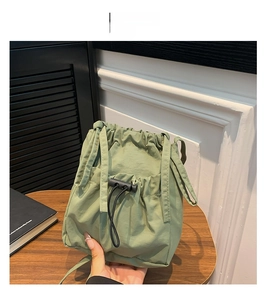 Detail view of a small green nylon drawstring bucket bag with black toggle fastener