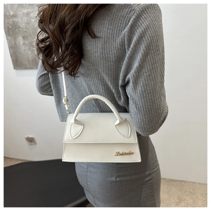 Detail of white leather mini crossbody bag with golden logo on ribbed knit outfit