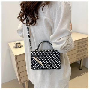 Detail of checkered shoulder bag with gold clasp and bear print pattern worn by model