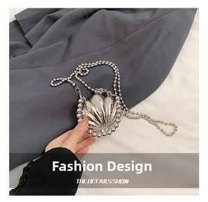 Detail of silver shell-shaped mini metal handbag with beaded chain and textured surface