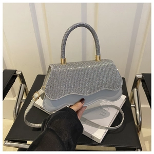 Détails d'un sac à main argenté serti de strass avec bord ondulé et finitions dorées