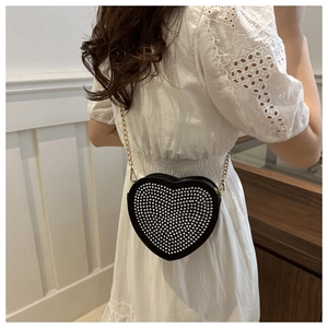 Detailed view of black heart-shaped handbag with silver rhinestones and gold chain strap