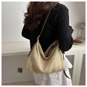 Détail d'un sac cabas en paille tressée avec bandoulière marron et fermeture éclair