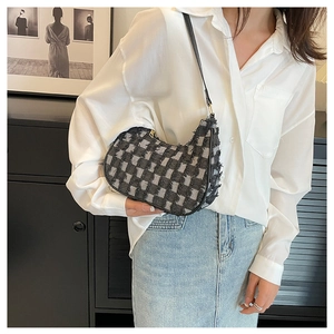 Détail du sac à bandoulière en toile à damier noir et blanc avec bords effilochés et cuir