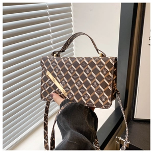 Detailed close-up of brown and white checkered crossbody bag with gold metal bar accent