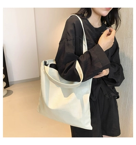 Dettaglio borsa tote bianco panna con cuciture geometriche e tracolla larga su modella