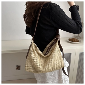 Détail d'un sac cabas en paille tissé main avec lanières en cuir marron sur un mannequin femme