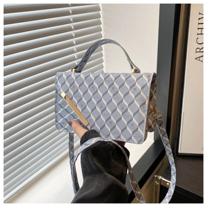 Detail of blue geometric plaid leather texture and gold metal bar on crossbody bag
