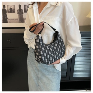 Gros plan du sac sous le bras en tweed à carreaux noir et blanc avec bords effilochés
