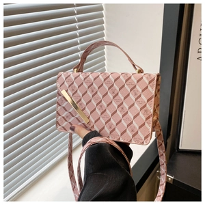 Detail of pink shoulder bag with bear patterns and gold metal bar buckle on flap