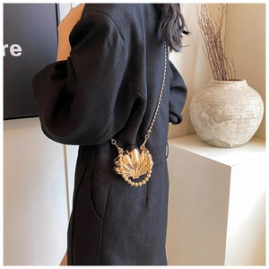 Detail view of a shell-shaped gold metallic mini crossbody bag with bead handle