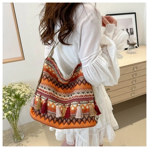 Close-up of bohemian woven tote bag with colorful geometric patterns and fringe tassels