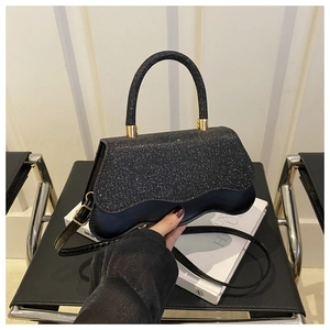Détail du sac bandoulière noir pailleté avec base ondulée et finitions en métal doré