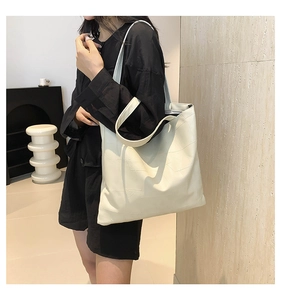 Dettaglio di una borsa tote bianco crema con trama patchwork geometrica e pelle sintetica