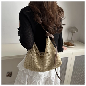 Detail of woven straw tote bag with brown leather strap and mesh texture on a model