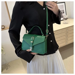 Deep green leather handbag featuring a vintage gold metal buckle and structured trapezoid shape