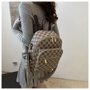 Detail view of large capacity plaid backpack featuring gold zippers and side pockets