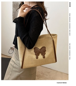 Detail of straw tote bag featuring a leather butterfly patch and slim brown shoulder straps