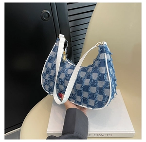 Détail du sac baguette en jean à carreaux bleus et blancs avec bords effilochés et cuir