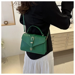 Detail of emerald green PU leather crossbody bag with envelope flap and gold hardware