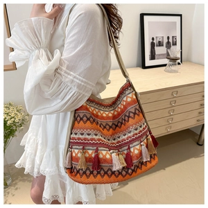 Detailed close-up of woven ethnic tote bag featuring vibrant geometric patterns and tassels