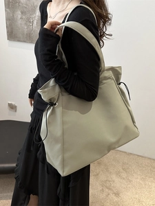 Large canvas tote bag with side drawstrings shown on model for daily commuting