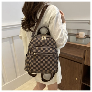 Detail of checkered mini backpack with adjustable straps worn by a model in a minimal room