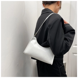 Detail of minimalist white glossy leather underarm bag on a black blazer outfit