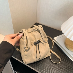 Beige nylon drawstring crossbody bag with adjustable strap in a minimalist style