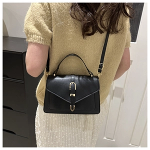 Detailed view of black leather handbag with a prominent golden U-shaped metal buckle lock