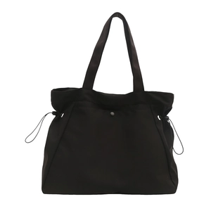Minimalist black nylon tote bag with drawstring sides and metal snap for daily commute
