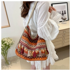 Detailed view of bohemian tote bag with orange wave patterns and colorful fringe
