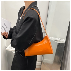 Fashion model wearing a bright orange patent leather baguette bag over the shoulder
