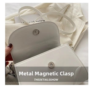 Nahaufnahme des eleganten Magnetverschlusses an einer weißen minimalistischen Handtasche