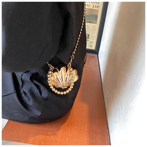 Detailed macro view of a gold shell-shaped mini crossbody bag with a beaded chain strap
