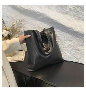 Dettaglio della borsa tote nera con cuciture geometriche bianche a contrasto in ecopelle