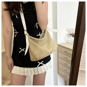 Détail d'un sac cabas en paille avec bandoulière en cuir blanc et boucle dorée
