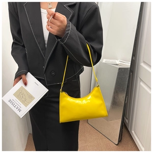 Detail of bright yellow patent leather baguette bag styled with a black blazer
