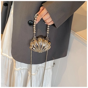 Detail of shell-shaped metallic crossbody bag with beaded handle and silver glossy finish