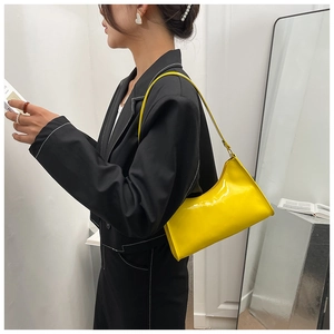 Glossy bright yellow patent leather baguette shoulder bag shown on model arm