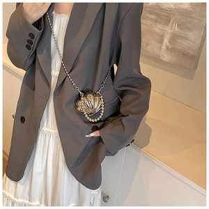Detailed view of silver shell-shaped mini bag with pearl trim and delicate ball chain