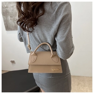 Dettaglio della borsa in pelle PU kaki con logo dorato indossata da una modella