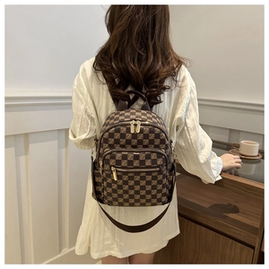 Detail of checkered brown backpack showing premium leather texture and golden zippers