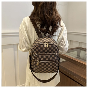 Detail of a brown checkered women backpack featuring gold zippers and double shoulder straps
