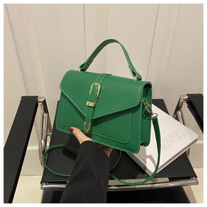 Detail of green faux leather crossbody bag with top handle and gold decorative buckle