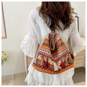 Detail showing bohemian woven tote bag with ethnic patterns and colorful fringe tassels