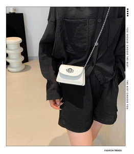 Detail shot of white mini crossbody bag with silver planet buckle and metal chain strap