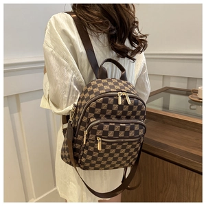 Close-up of checkered brown backpack showing dual gold zippers and side pocket detail